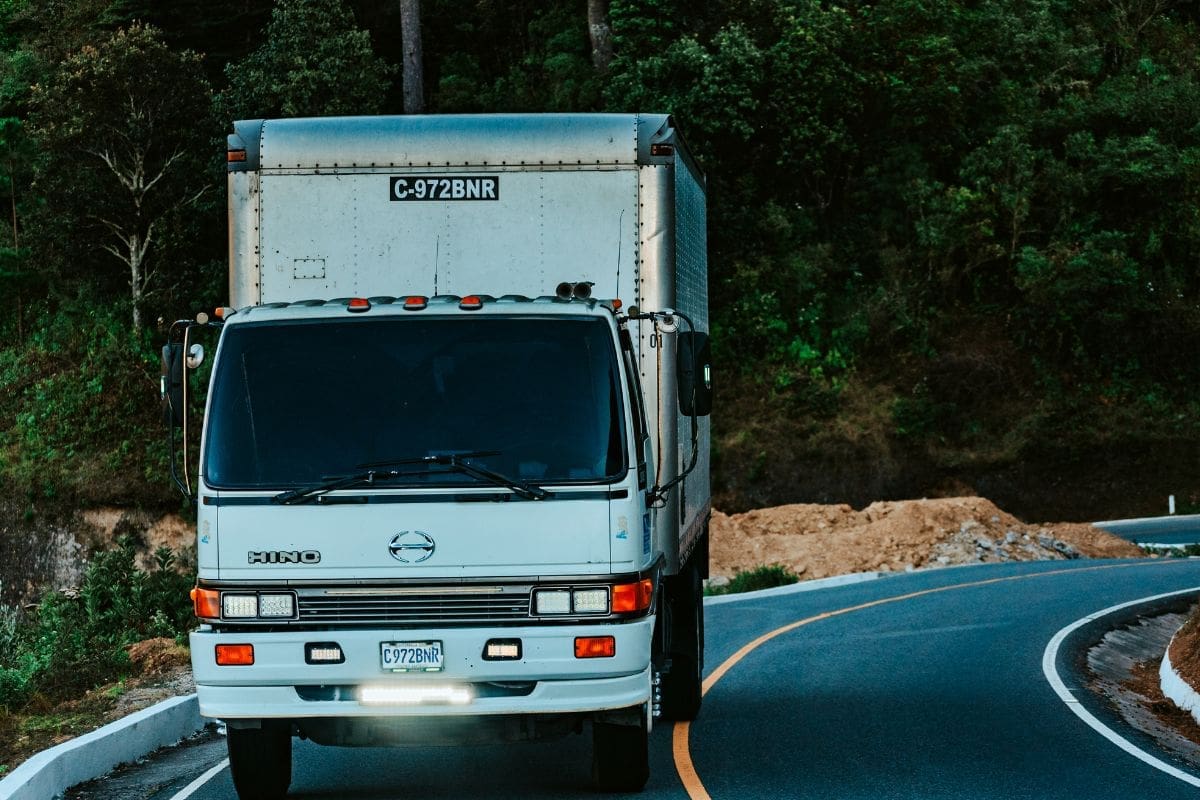 Showcasing a big white truck maneuvering on curve road