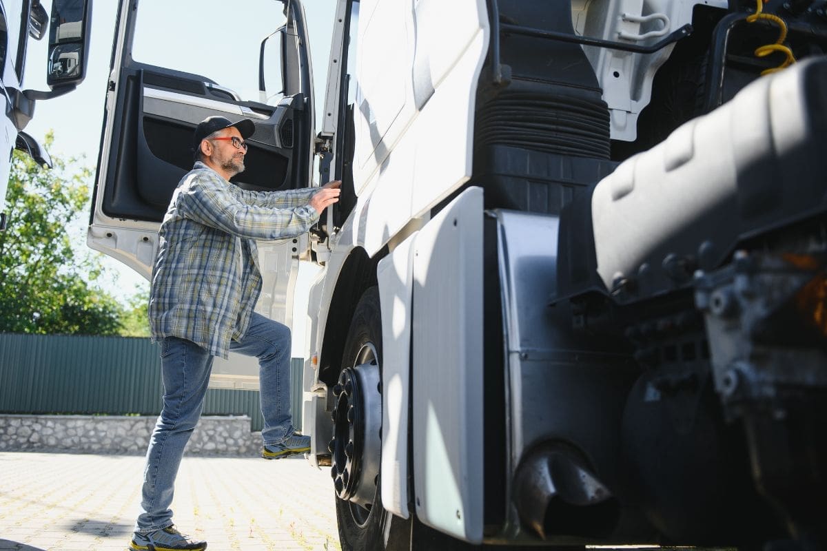 The truck driver is about to climb up to his rig